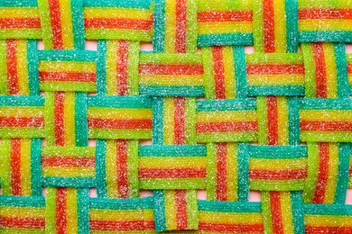 Photo of Tasty rainbow sour belts on pink background, top view