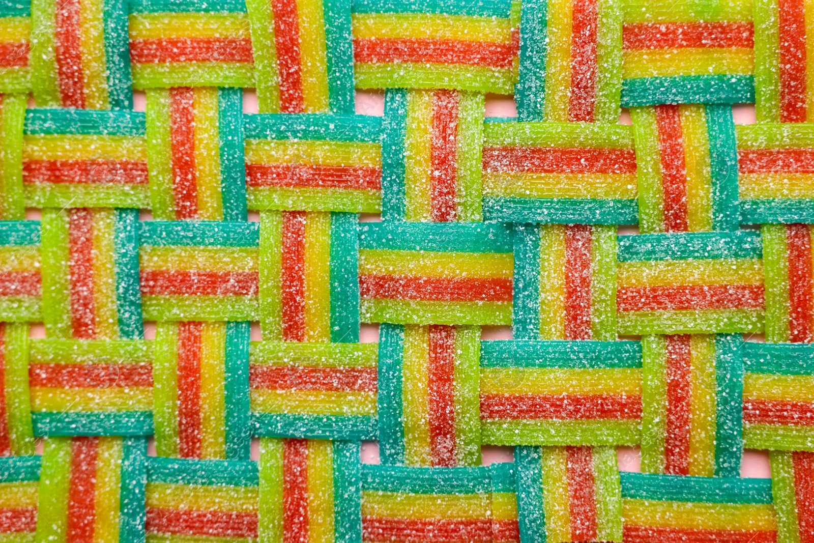 Photo of Tasty rainbow sour belts on pink background, top view