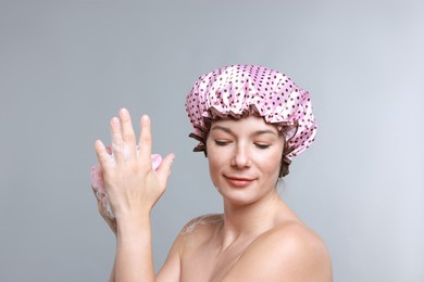 Photo of Woman with shower cap and mesh sponge on grey background