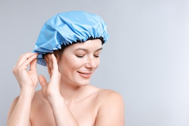 Photo of Woman wearing shower cap on grey background, space for text