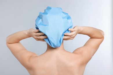 Photo of Woman wearing shower cap on grey background, back view