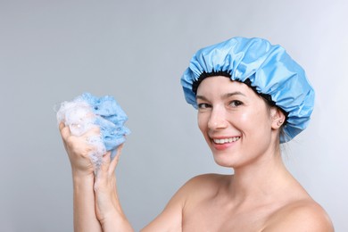 Photo of Woman with shower cap and mesh sponge on grey background