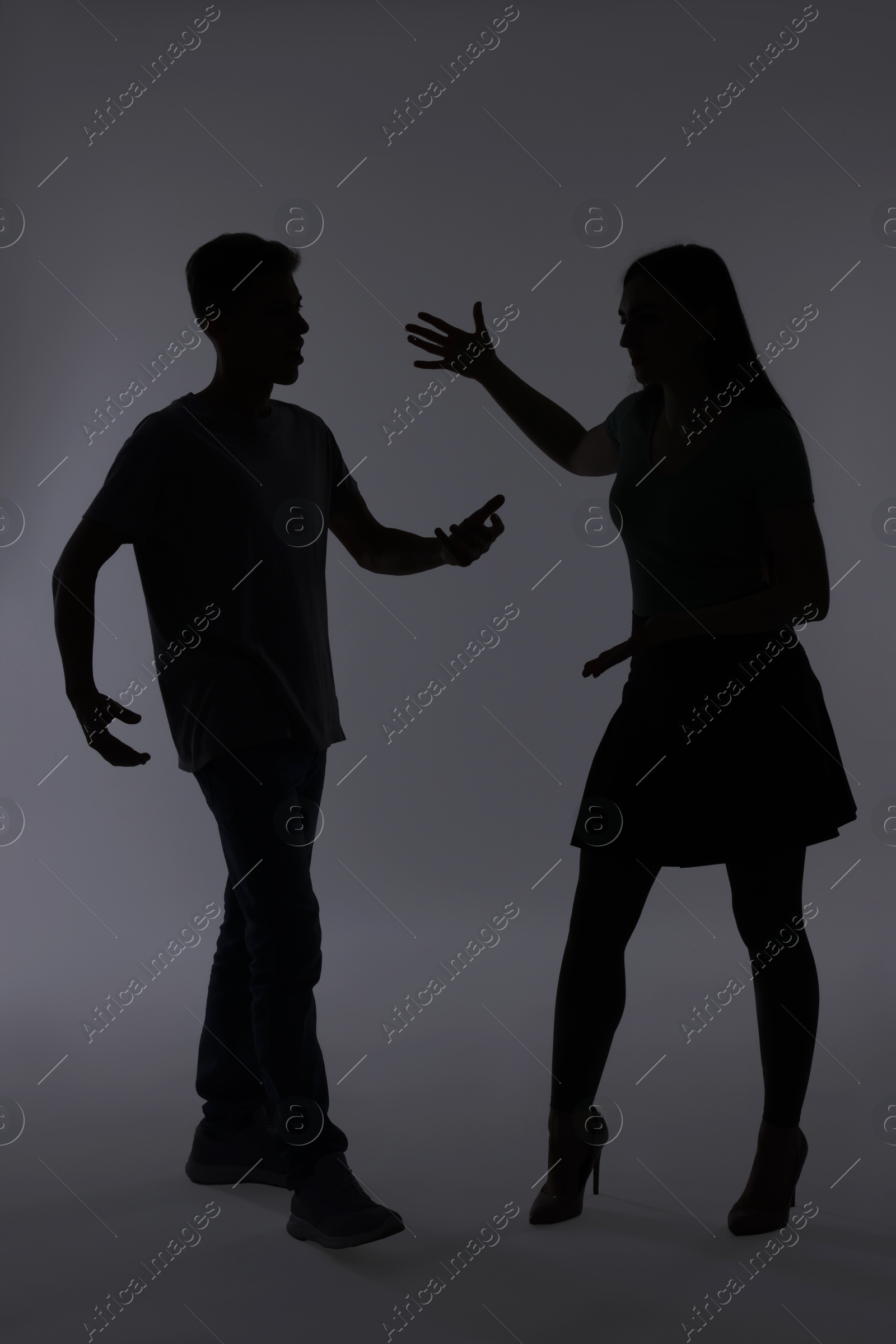 Photo of Domestic violence. Silhouette of couple quarreling on grey background