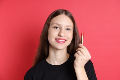 Photo of Smiling teenage girl with lipstick on red background