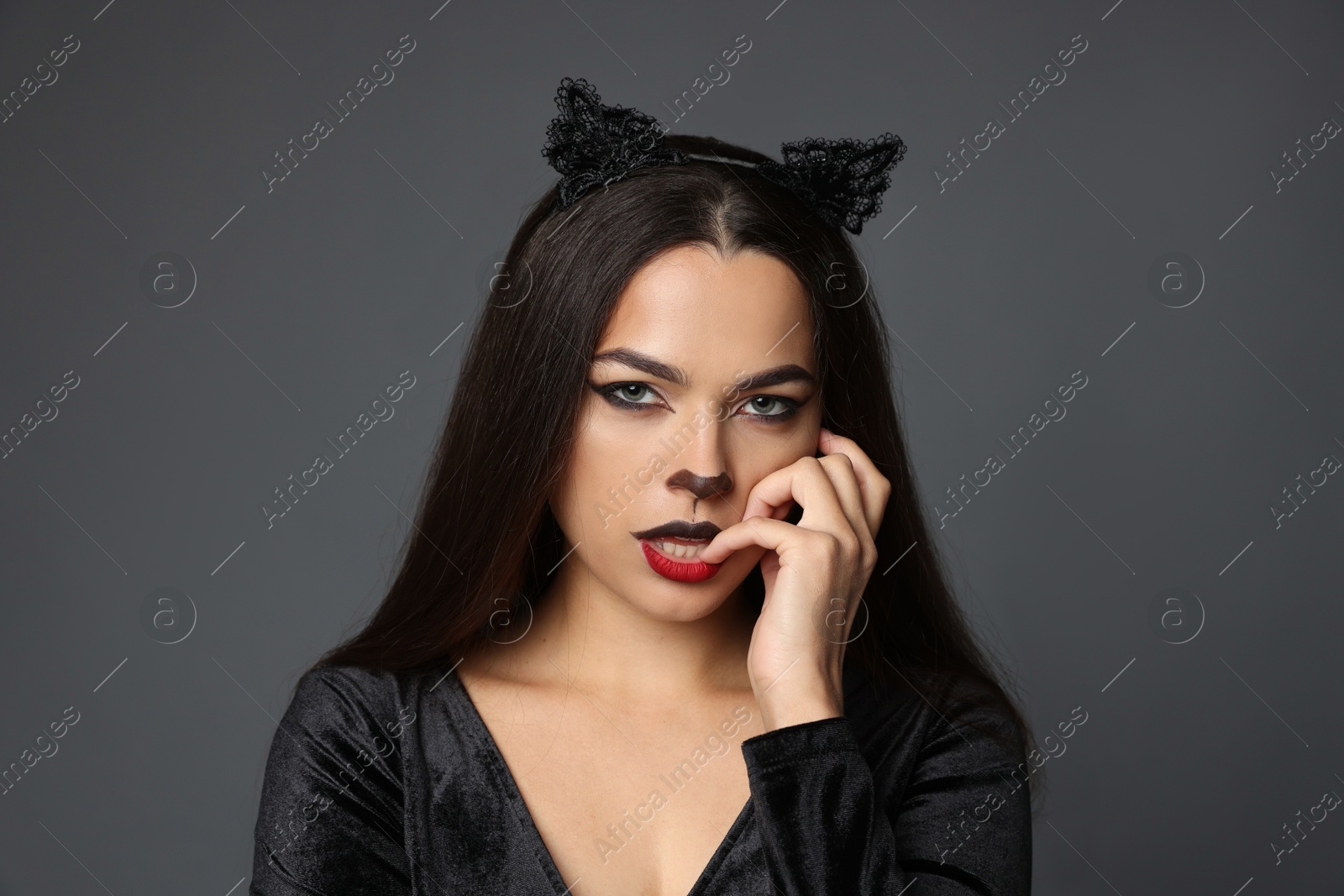 Photo of Attractive woman with cat makeup and ears on grey background