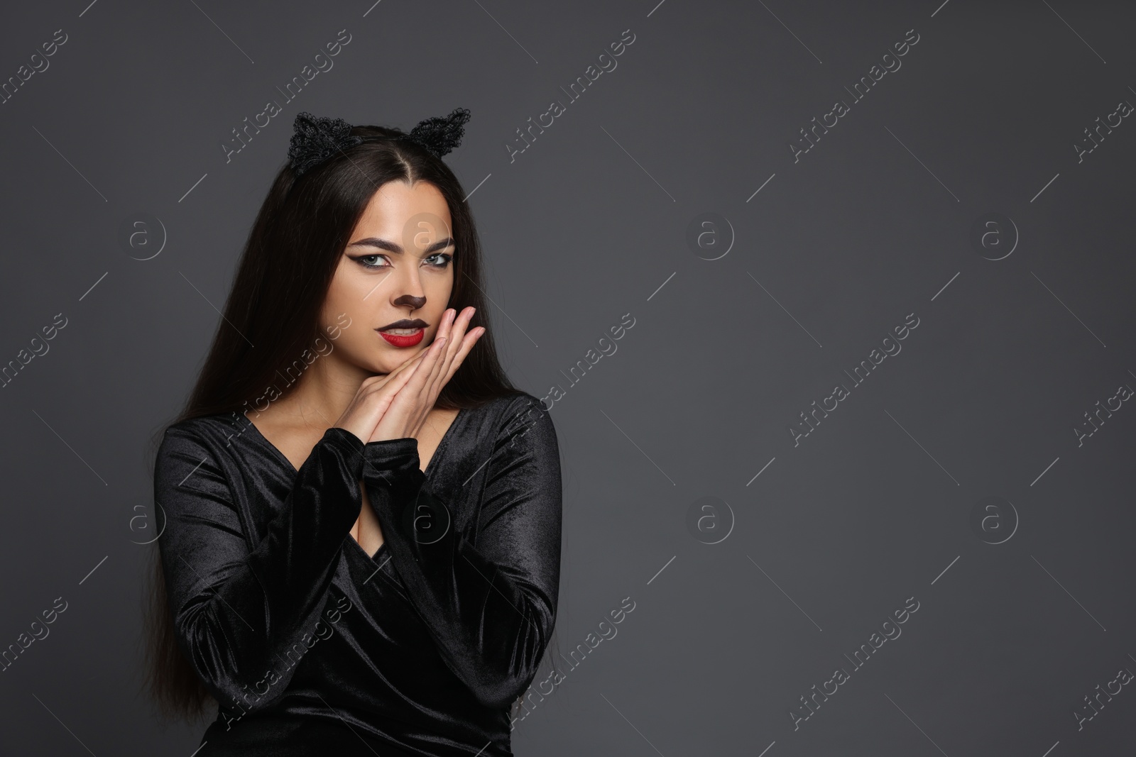 Photo of Attractive woman with cat makeup and ears on grey background. Space for text