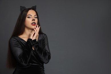 Photo of Attractive woman with cat makeup and ears on grey background. Space for text