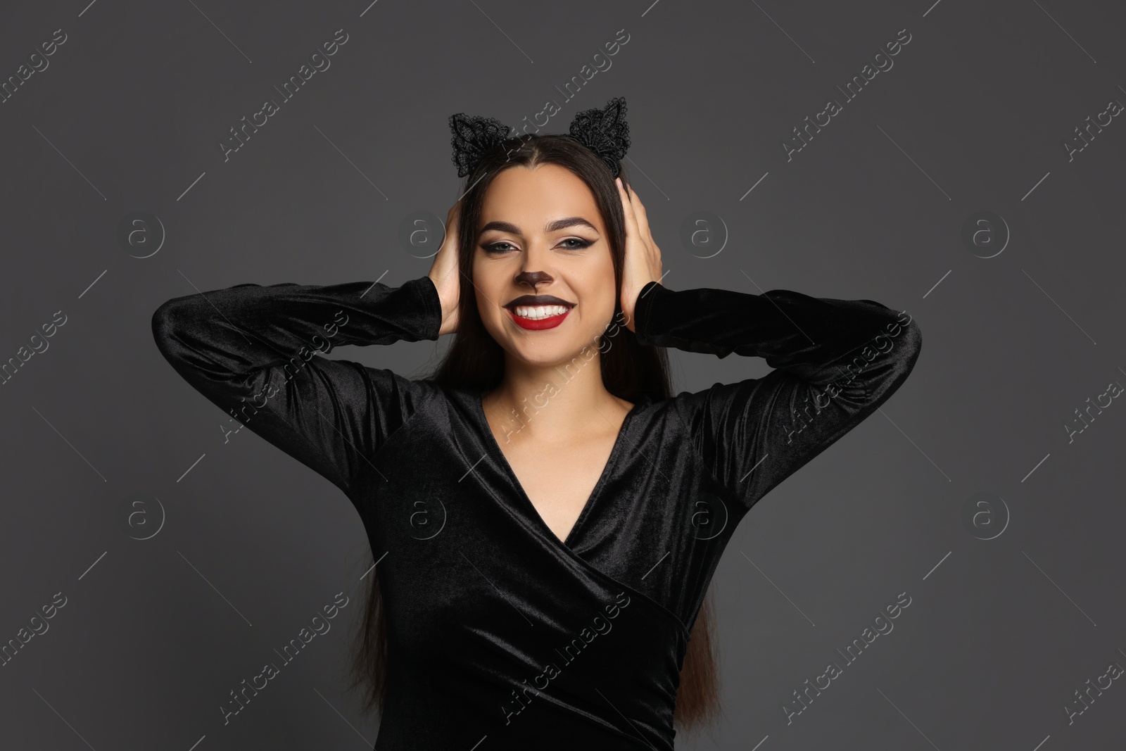 Photo of Attractive woman with cat makeup and ears on grey background