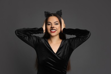 Photo of Attractive woman with cat makeup and ears on grey background