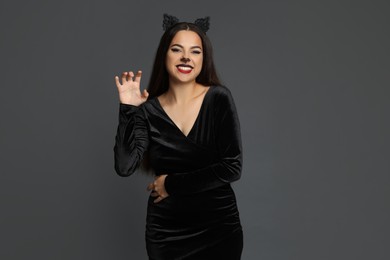 Photo of Attractive woman with cat makeup and ears on grey background