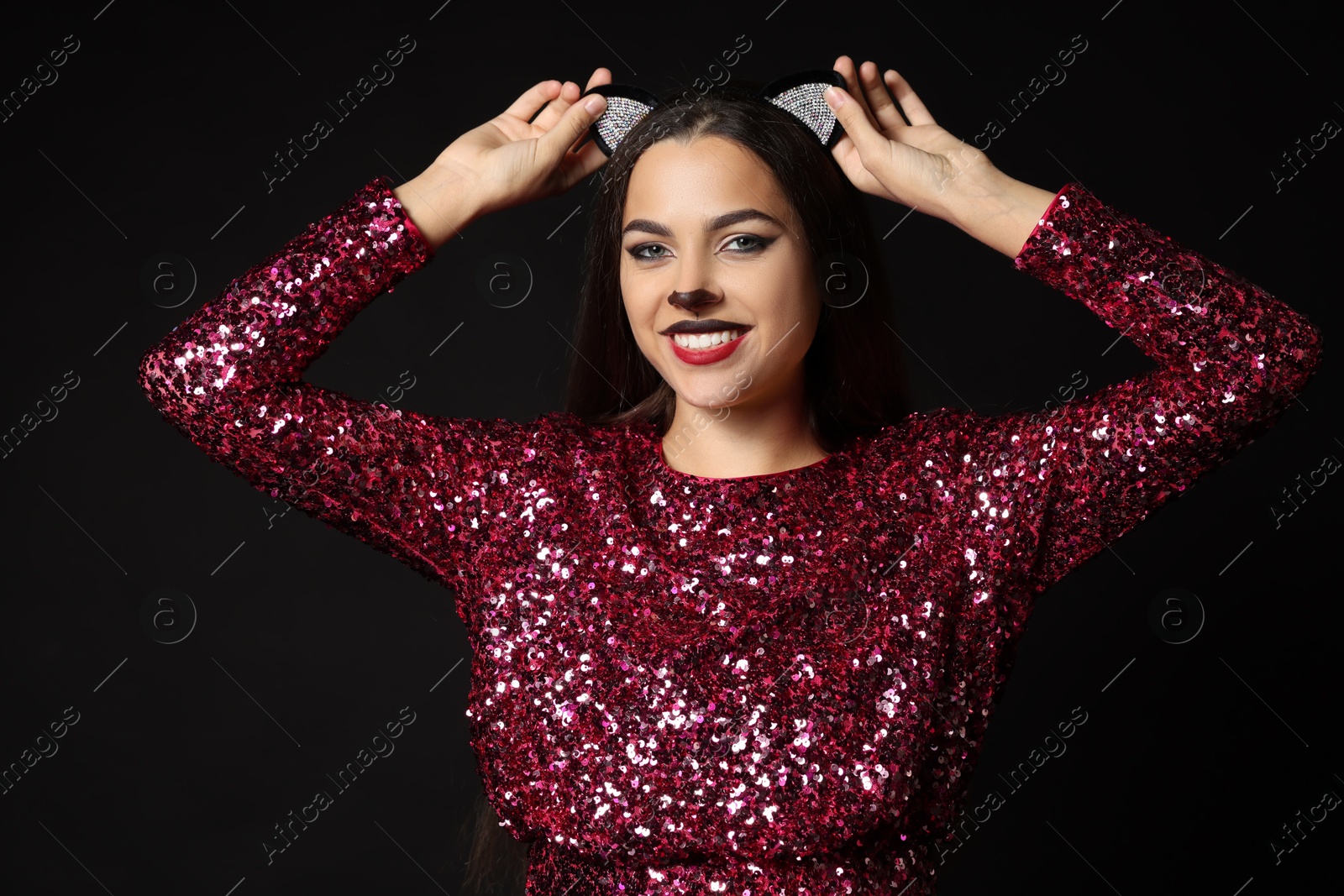 Photo of Charming woman with cat makeup and ears on black background