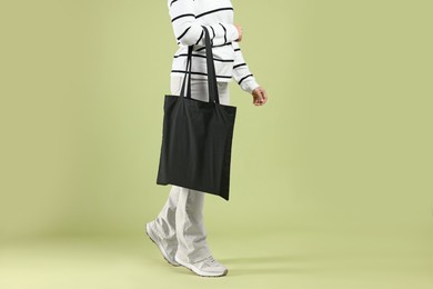 Photo of Woman with blank black shopper bag on color background, closeup. Mockup for design