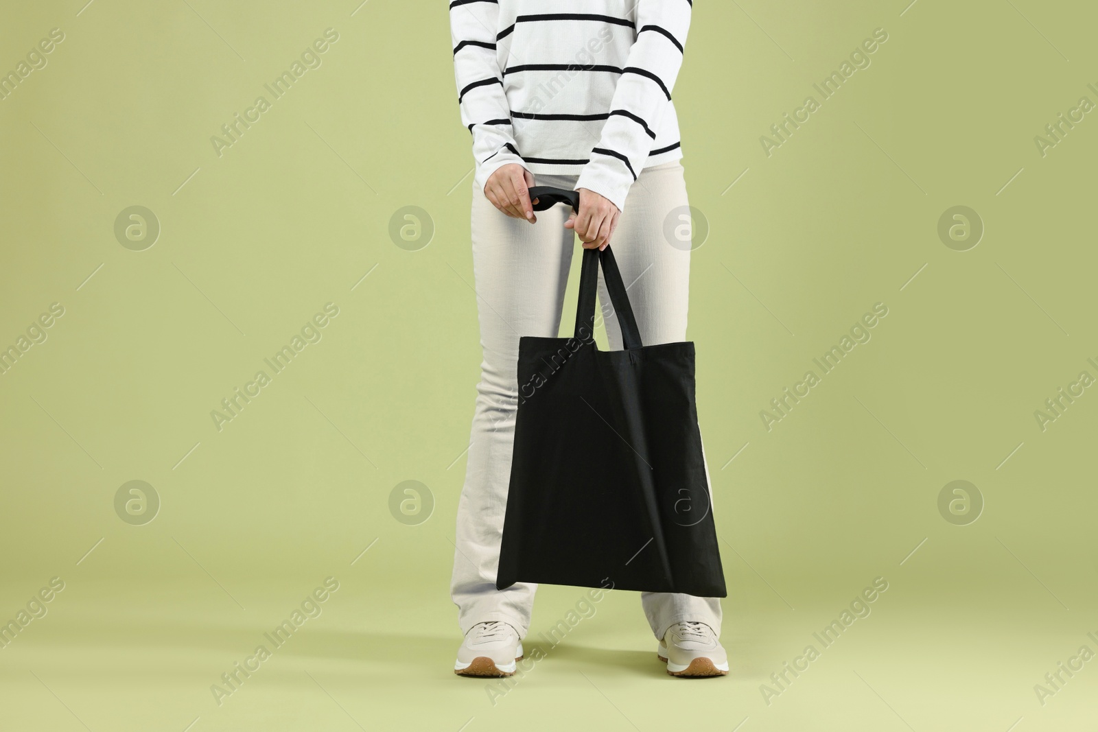 Photo of Woman with blank black shopper bag on color background, closeup. Mockup for design