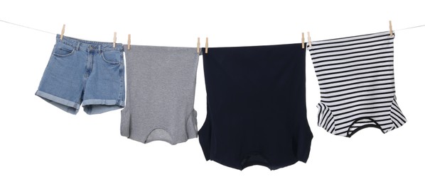 Different clothes drying on laundry line against white background