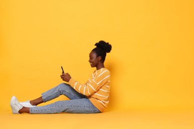 Photo of Happy woman with smartphone on yellow background. Space for text