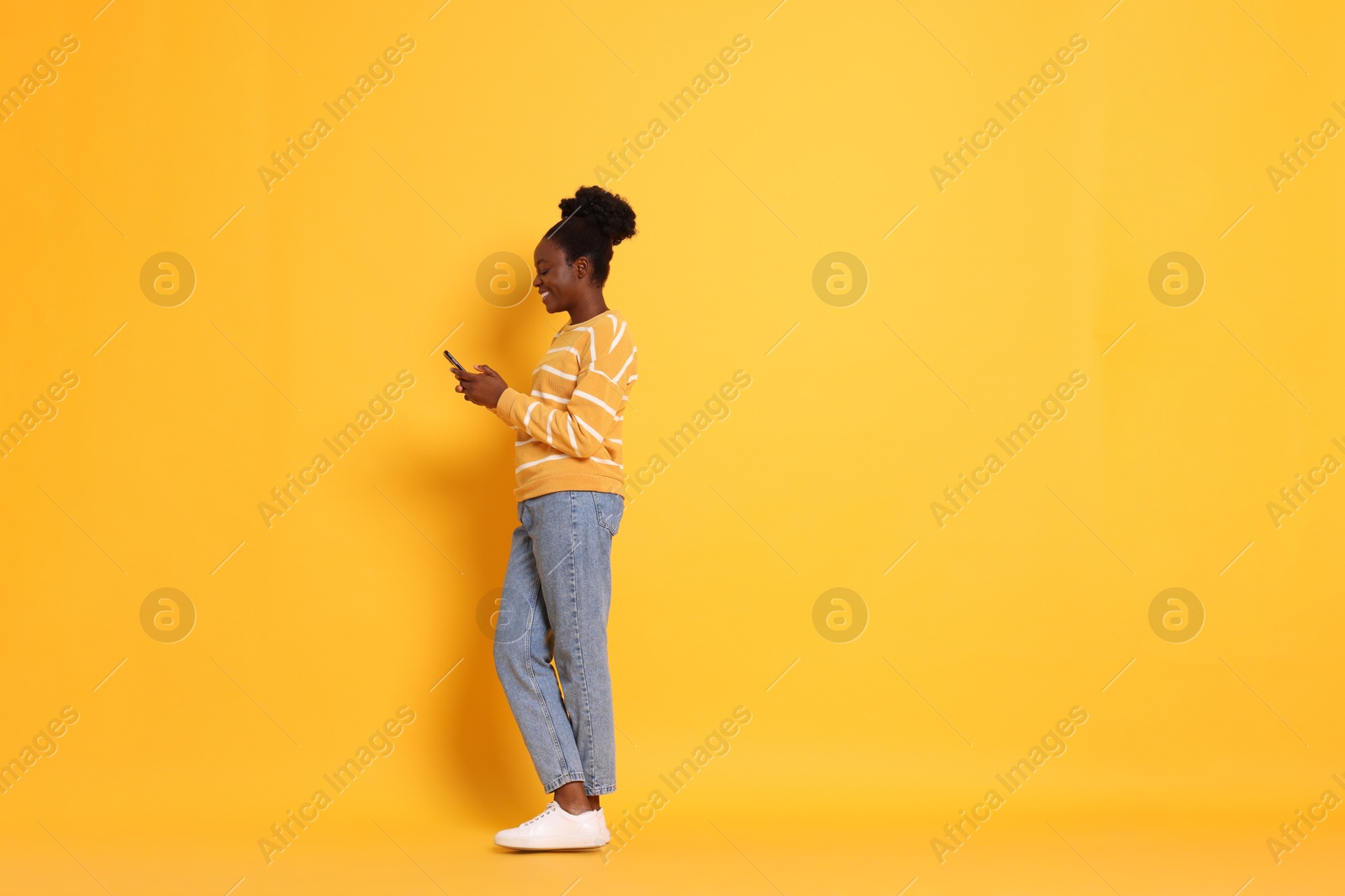 Photo of Happy woman with smartphone on yellow background. Space for text