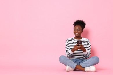 Photo of Happy woman with smartphone on pink background. Space for text