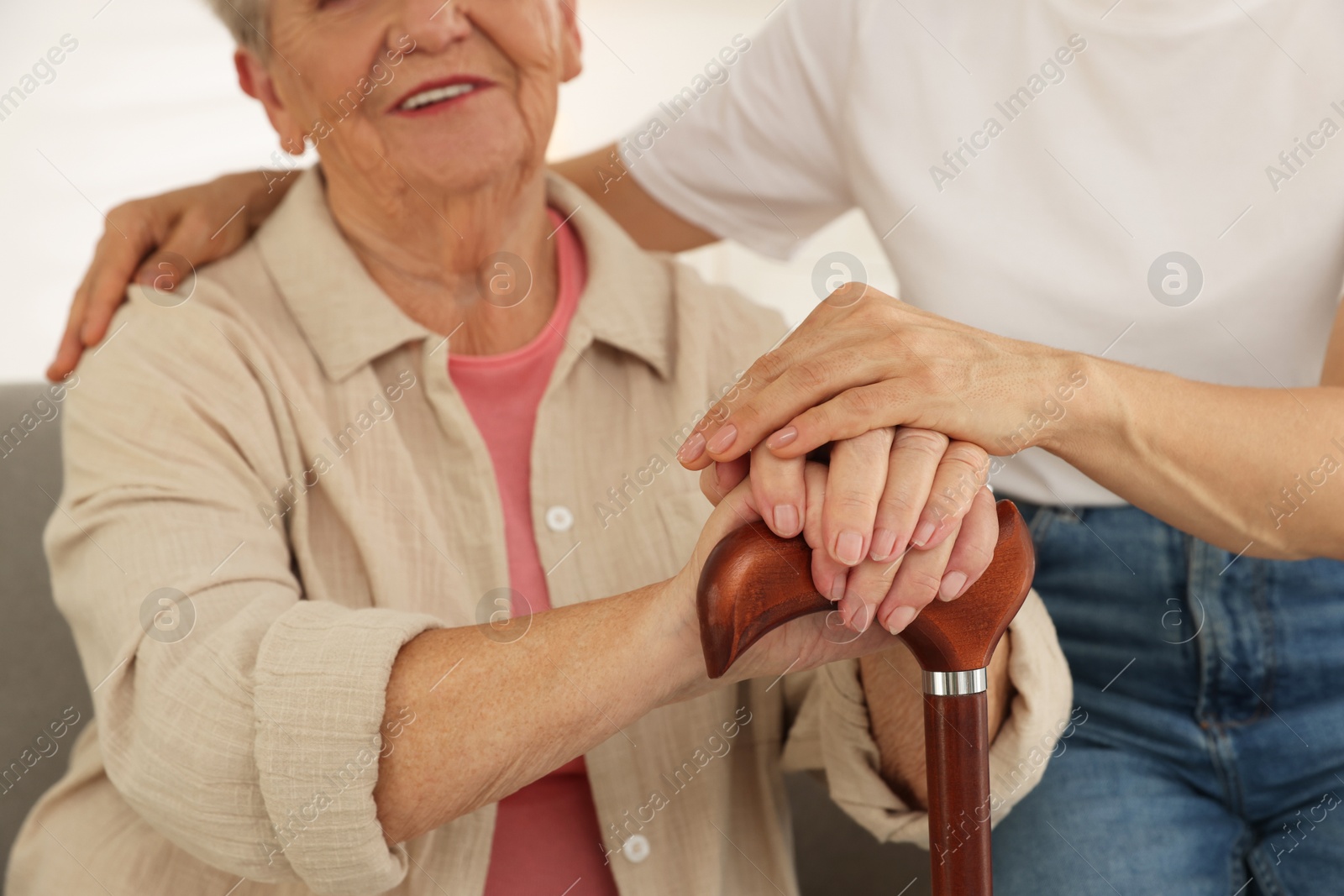 Photo of Caregiver supporting senior woman at home, closeup