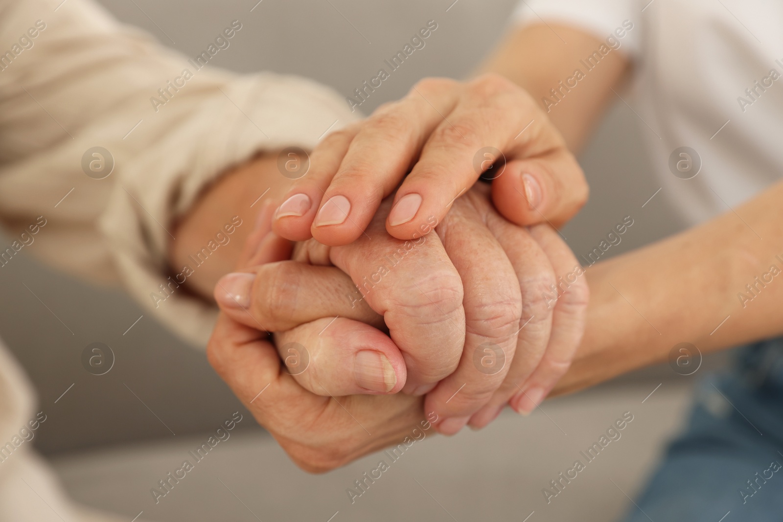 Photo of Caregiver supporting senior woman at home, closeup