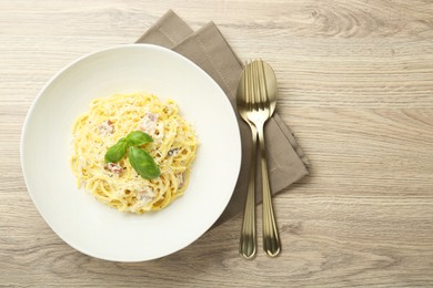 Photo of Delicious pasta Carbonara served on wooden table, flat lay