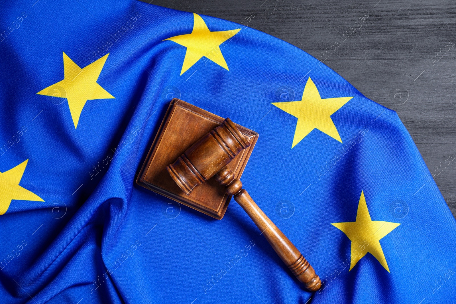 Photo of Judge's gavel and flag of European Union on grey wooden table, top view