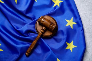 Photo of Judge's gavel and flag of European Union on light grey table, top view