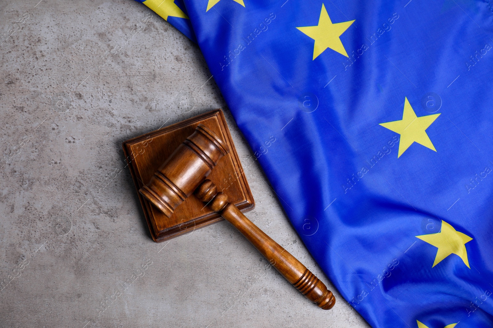 Photo of Judge's gavel and flag of European Union on grey table, top view