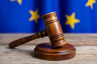 Photo of Judge's gavel on wooden table against European Union flag, closeup