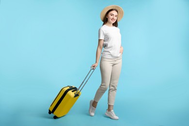 Photo of Woman in straw hat with suitcase on light blue background