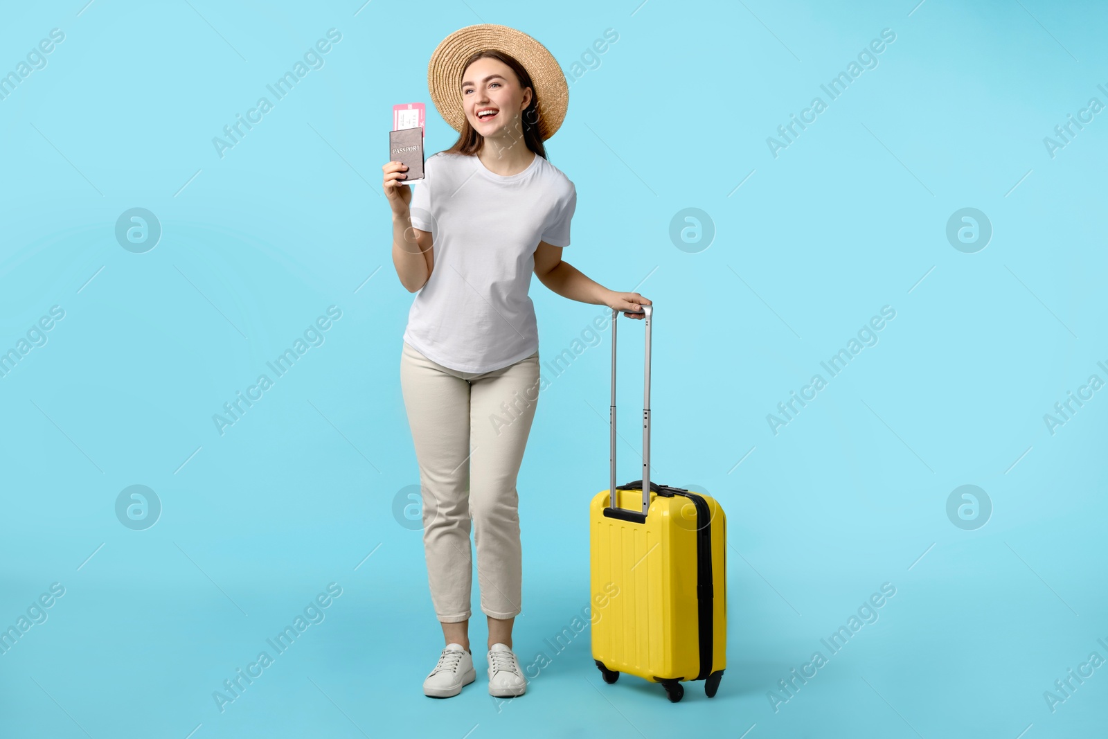 Photo of Woman with ticket, passport and suitcase on light blue background