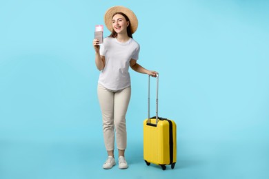 Photo of Woman with ticket, passport and suitcase on light blue background