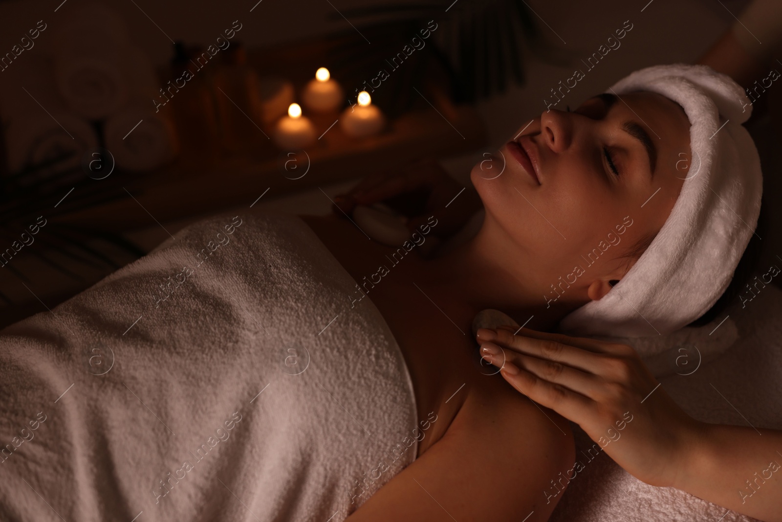 Photo of Young woman receiving hot stone massage in spa salon