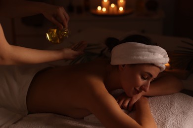 Photo of Young woman receiving massage with essential oil in spa salon