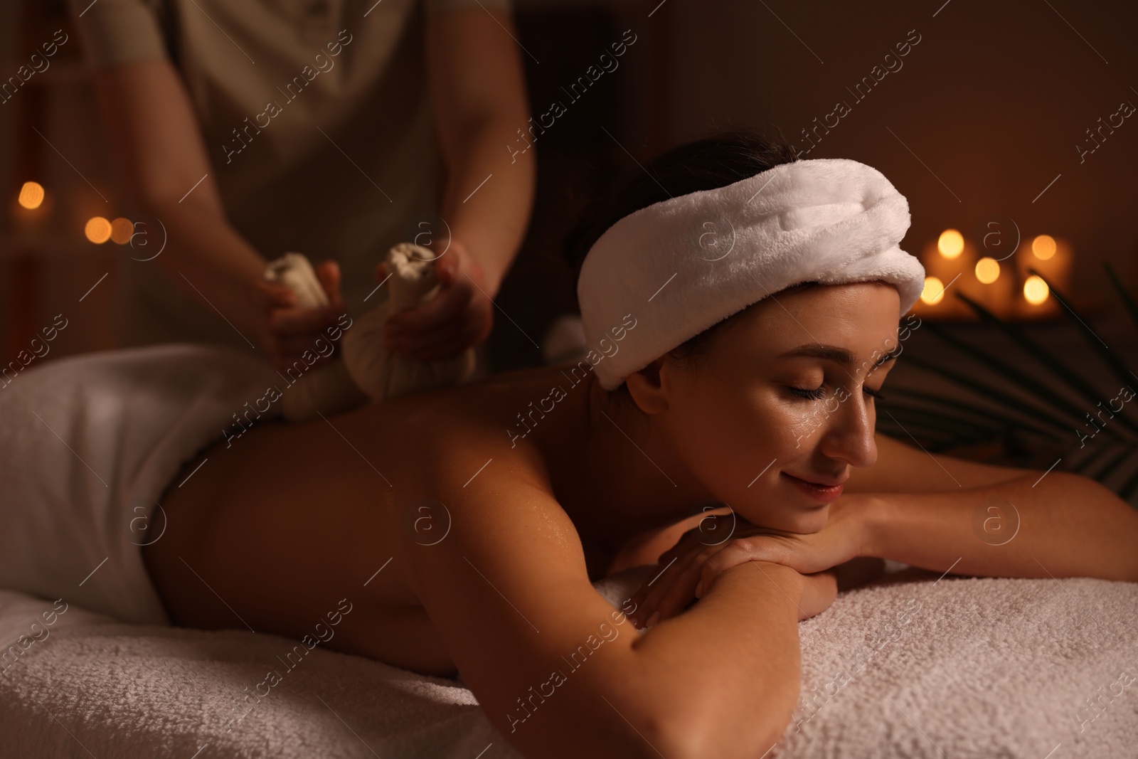 Photo of Young woman receiving back massage with herbal bags in spa salon