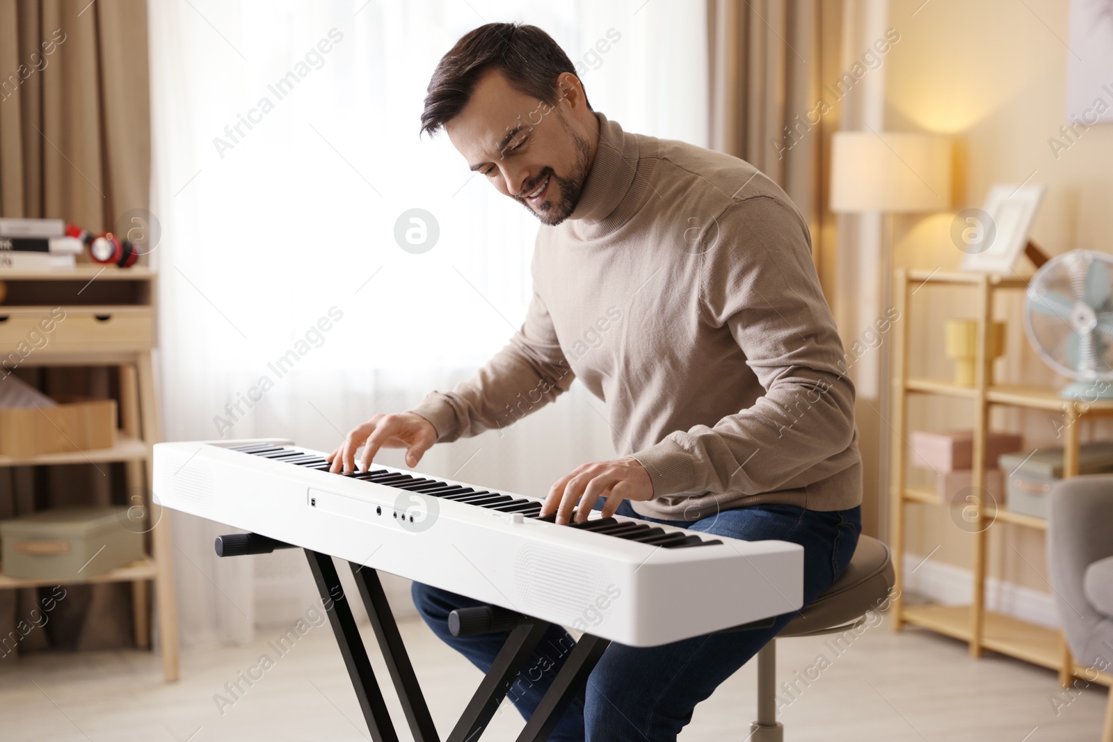 Photo of Smiling man playing synthesizer at home. Electronic musical instrument