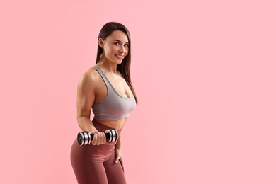 Photo of Woman in gym clothes exercising with dumbbell on pink background, space for text