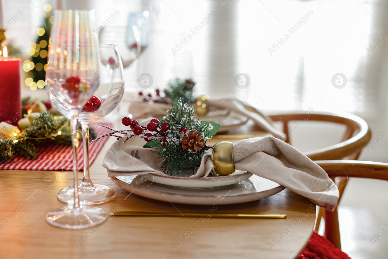 Photo of Christmas celebration. Festive table setting with dishware, glasses and decor in room, closeup