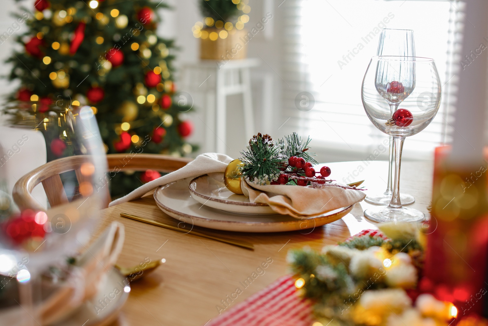 Photo of Christmas celebration. Festive table setting with dishware, glasses and decor in room