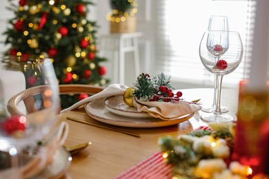 Photo of Christmas celebration. Festive table setting with dishware, glasses and decor in room