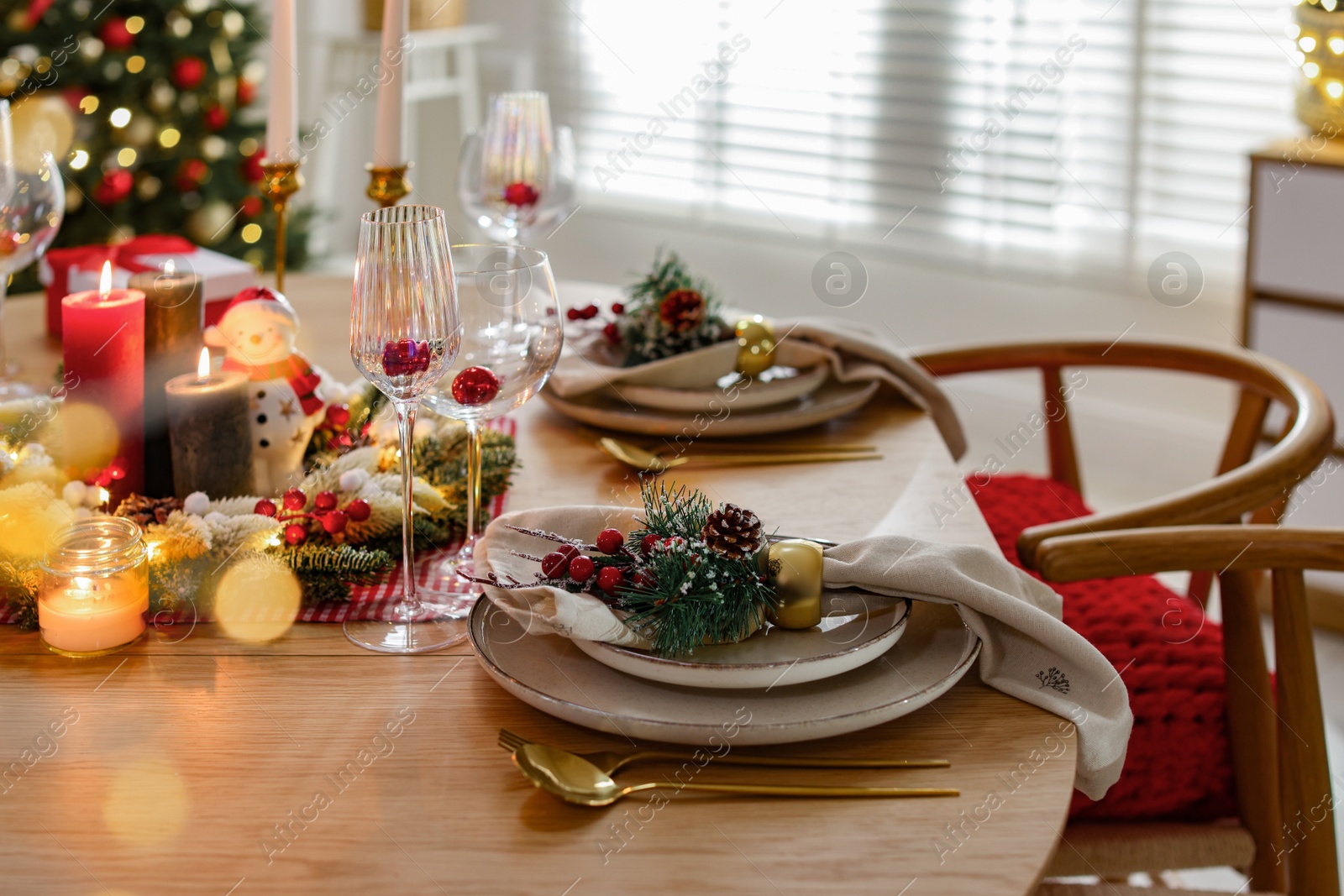 Photo of Christmas celebration. Festive table setting with dishware, glasses and decor in room