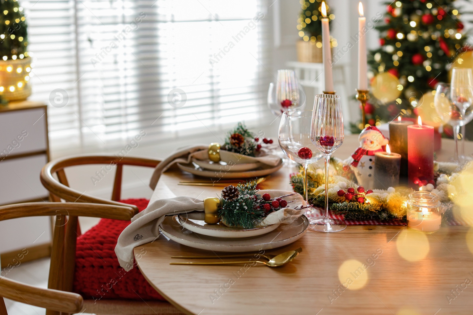 Photo of Christmas celebration. Festive table setting with dishware, glasses and decor in room