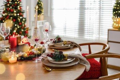 Photo of Christmas celebration. Festive table setting with dishware, glasses and decor in room