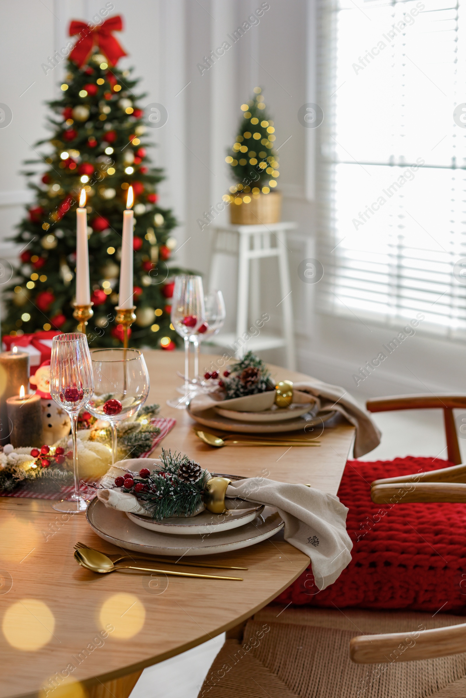 Photo of Christmas celebration. Festive table setting with dishware, glasses and decor in room