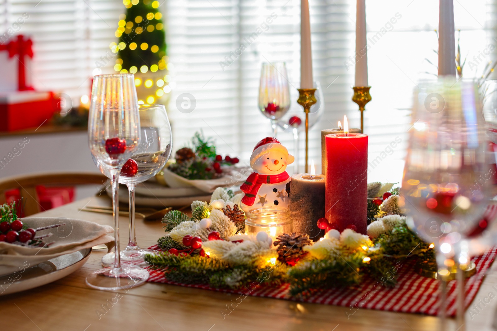 Photo of Christmas place setting with festive decor on wooden table in room