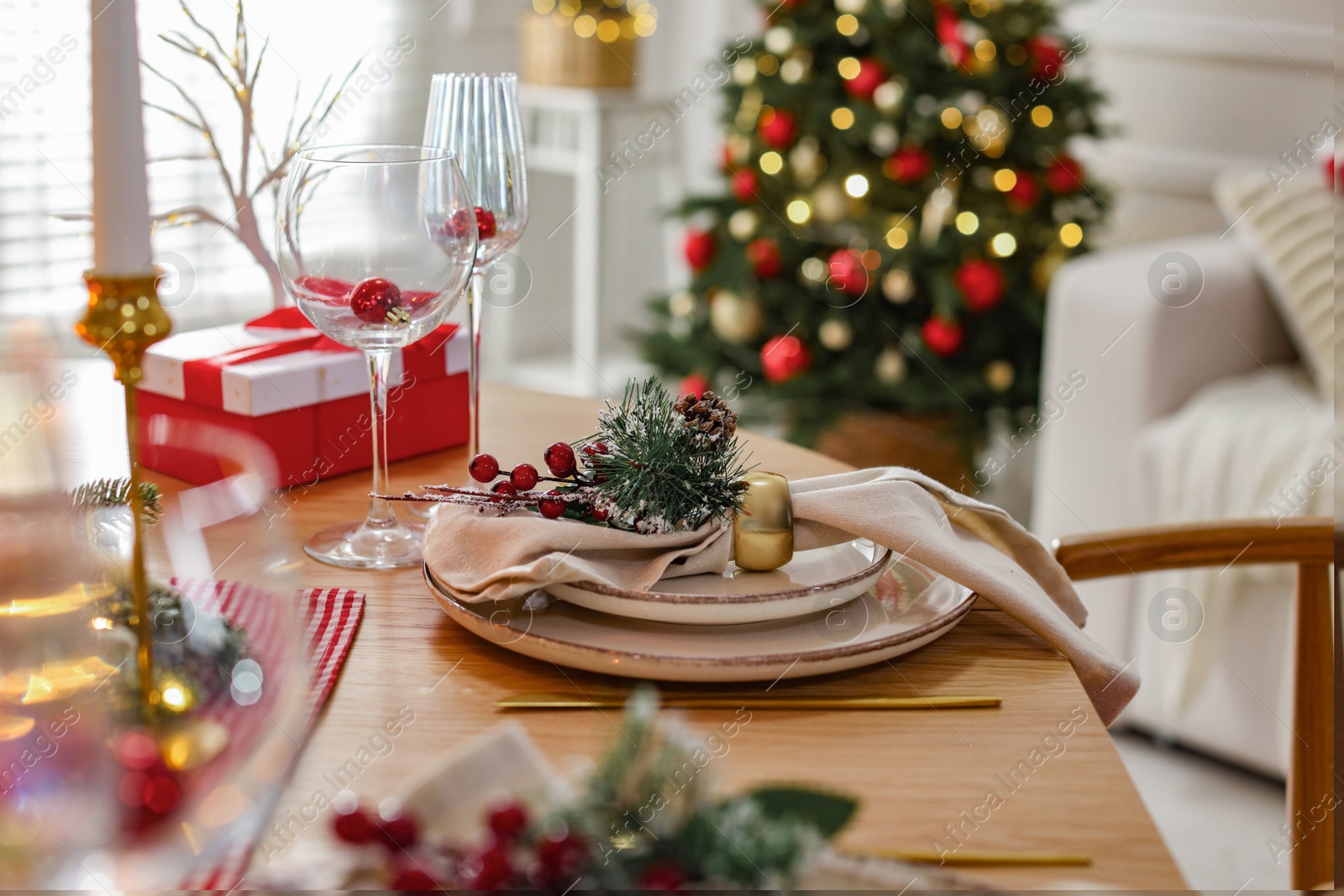 Photo of Christmas place setting with festive decor on wooden table in room