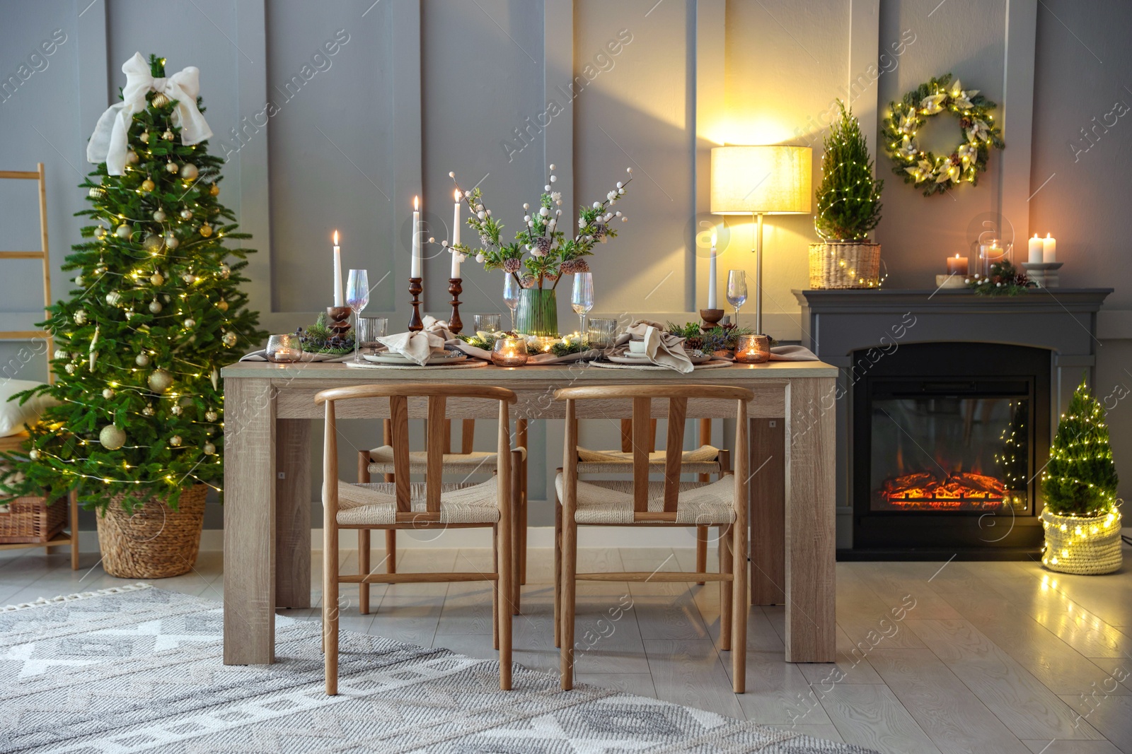 Photo of Christmas table setting with stylish dishware, glasses and burning candles in festive decorated room