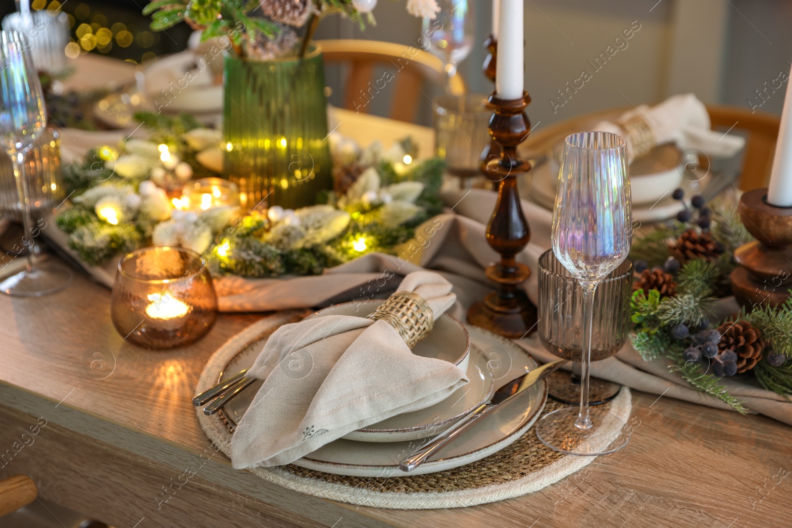 Photo of Christmas place setting with festive decor on wooden table in room