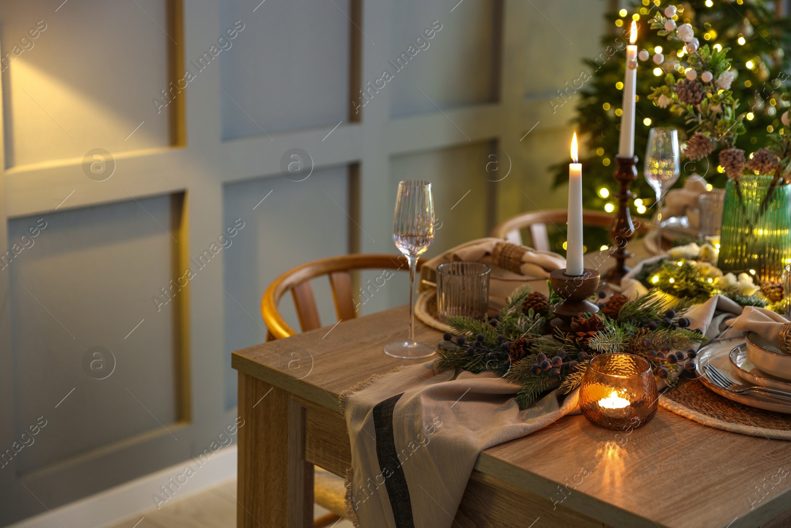 Photo of Christmas celebration. Festive table setting with dishware, glasses and decor in room