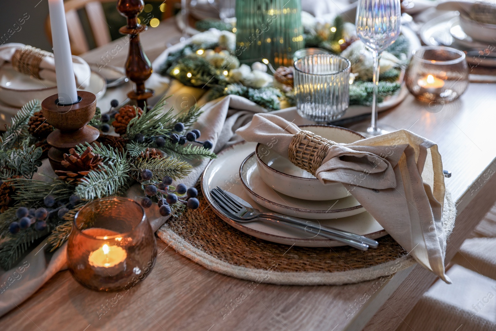 Photo of Christmas place setting with festive decor on wooden table in room