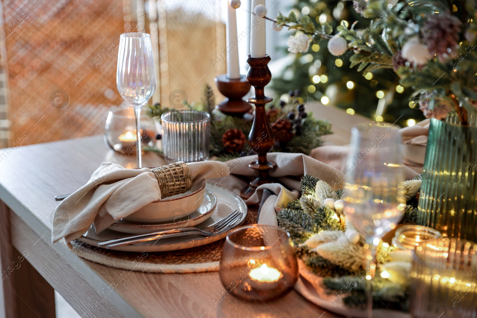 Photo of Christmas place setting with festive decor on wooden table in room